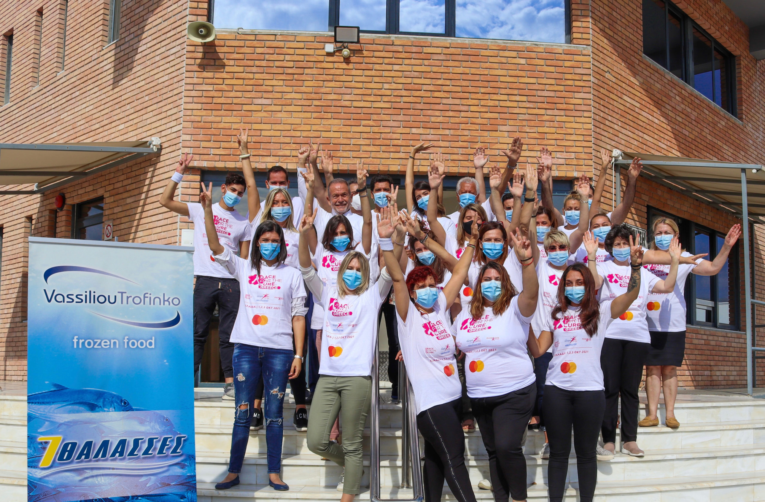 Η ομάδα συμμετεχόντων της ΒΑΣΙΛΕΙΟΥ ΤΡΟΦΙΝΚΟ στον αγώνα Race for the Cure, με τα συλλεκτικά t-shirts της διοργάνωσης, μπροστά στην είσοδο του εργοστασίου στη Μαγούλα Αττικής.